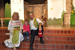 Prinzessin Rosalie und der Prinz mit einem Kind aus dem Publikum vor der Bühnenkulisse.
