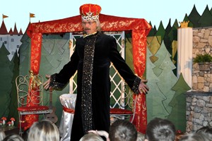 Der König steht im Schlosspark und spricht zu den Kindern im Publikum.
