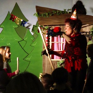 Hexe Schmusemund und ein Mädchen aus dem Publikum tanzen mit Hexenbesen. Hexe Schmusemund hat dabei einen großen Marienkäfer auf ihrer linken Hand.